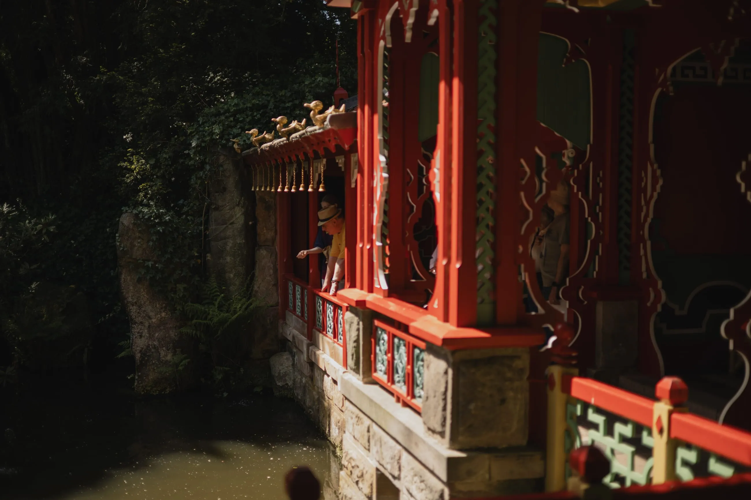 Red lacquered Chinese pavilion in deep shade by water