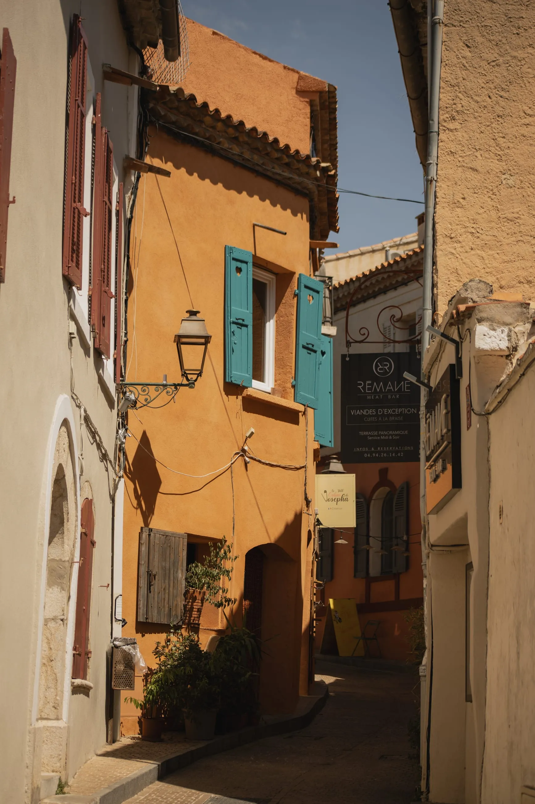 Ochre house with teal shutters in a narrow lane