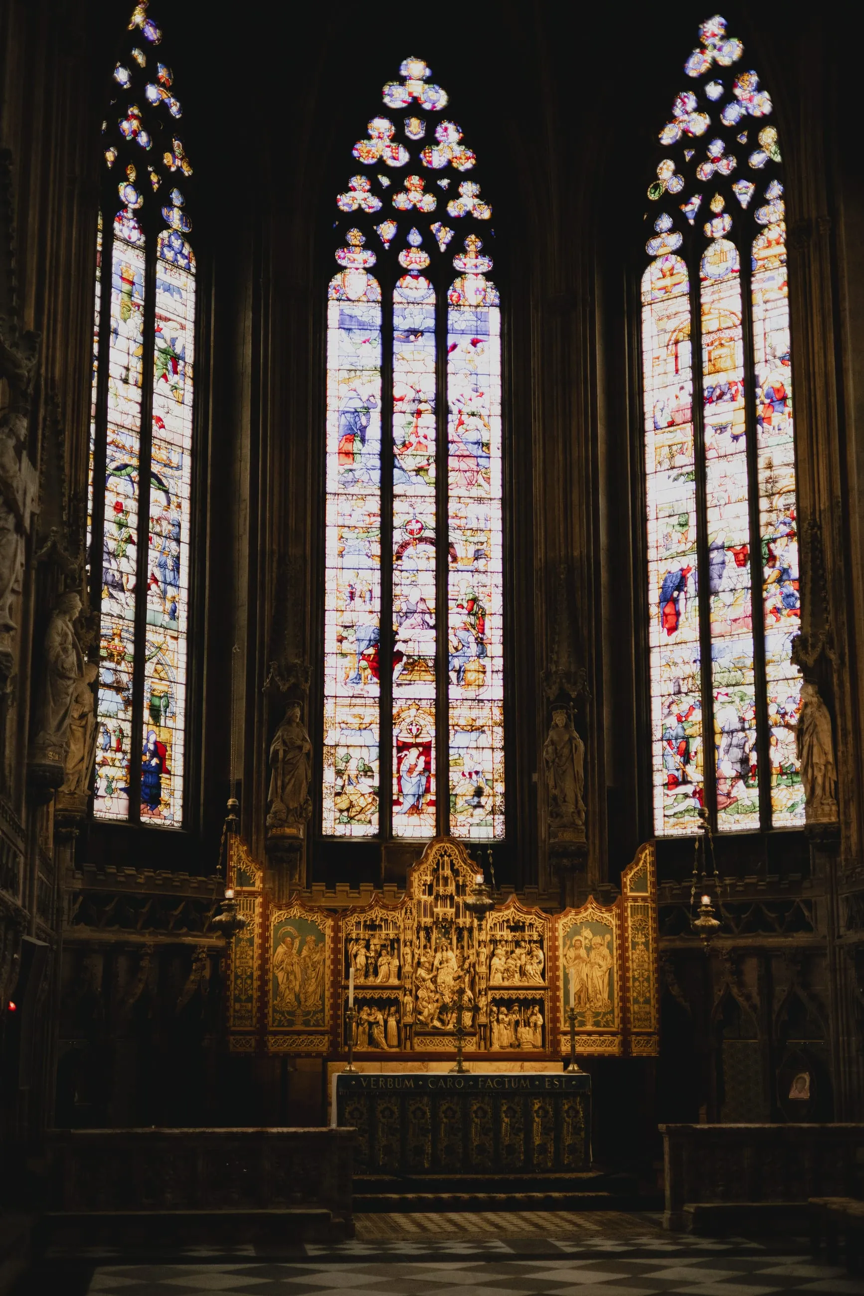 Tall stained-glass windows above a gilded altar