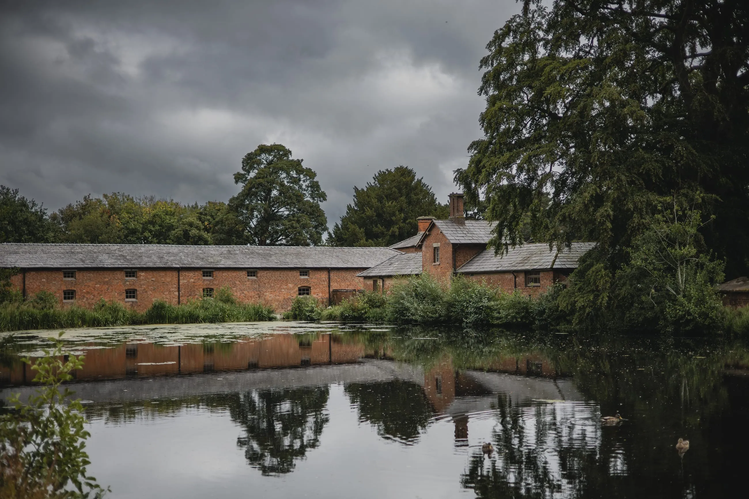 Brick estate buildings reflected in a still river