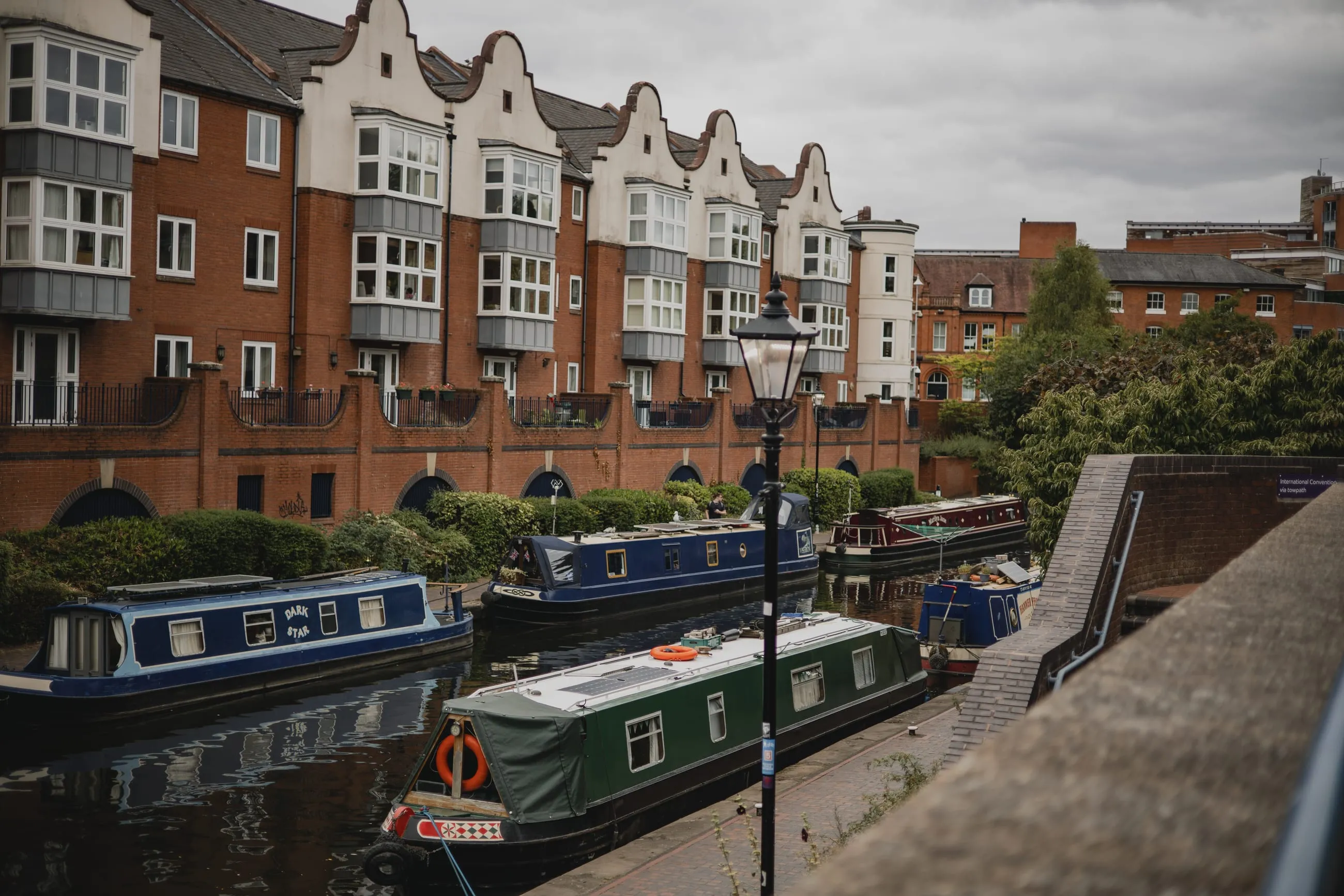 Narrowboats moored below red-brick canal-side flats