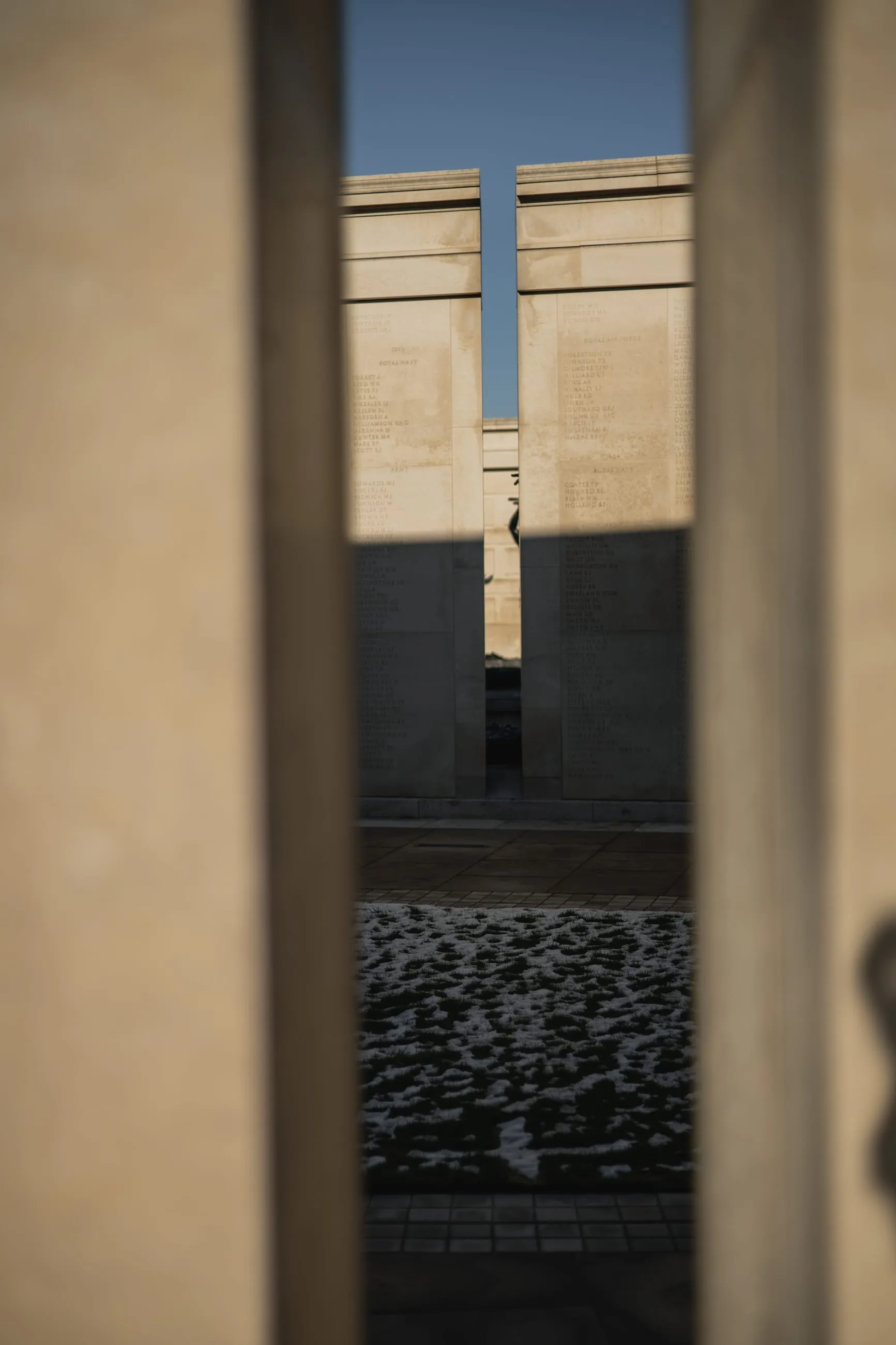 Memorial wall glimpsed through a narrow stone gap