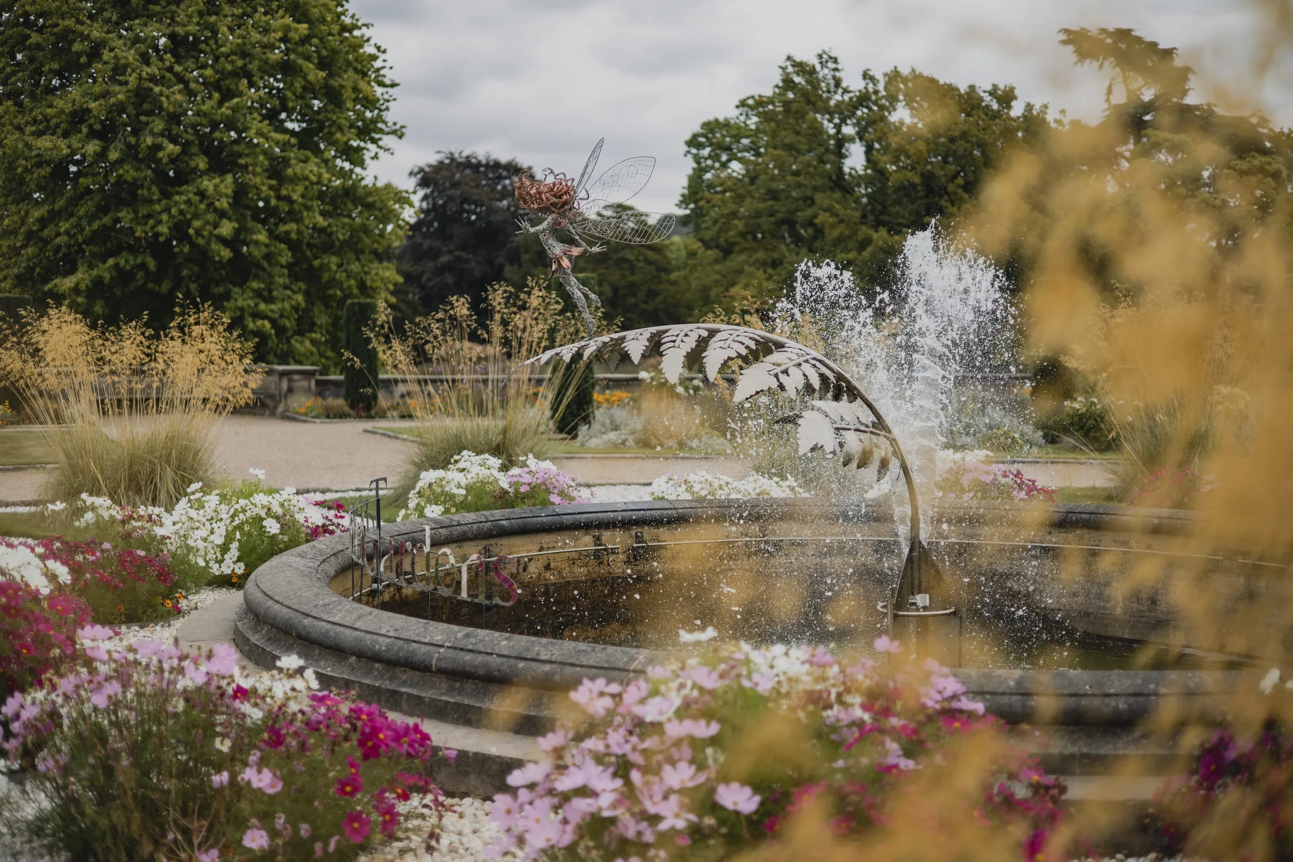 Fountain and wire sculpture in a flower garden