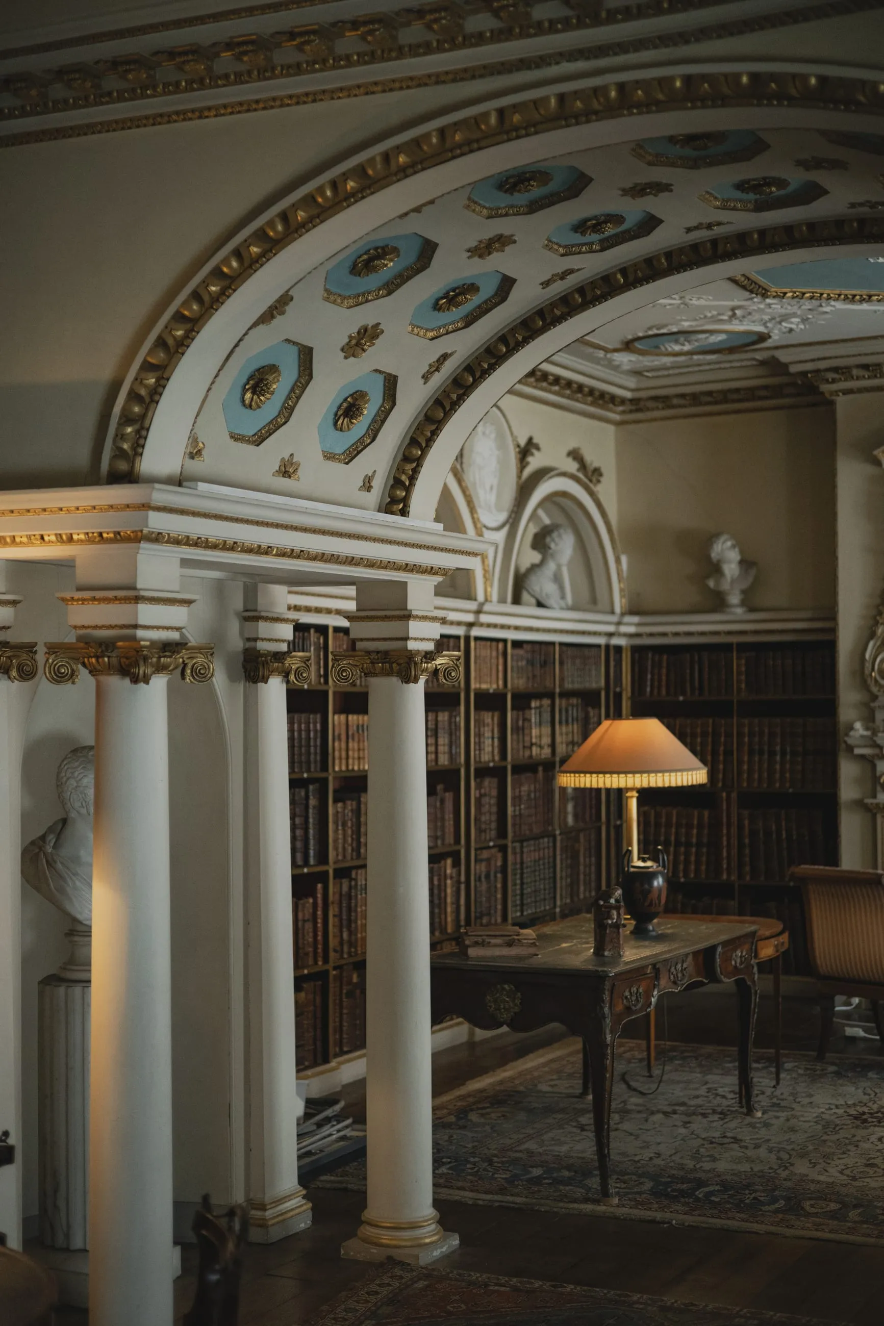 Arched library interior with columns and lamp