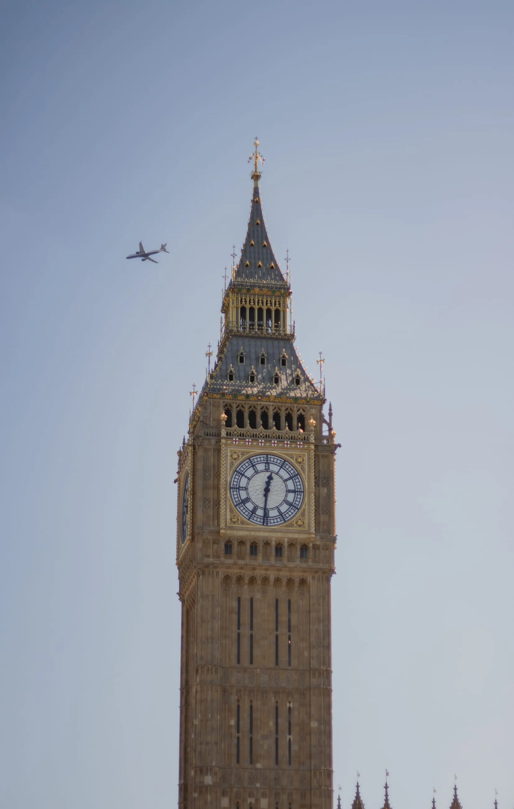 Elizabeth Tower against blue sky, plane overhead