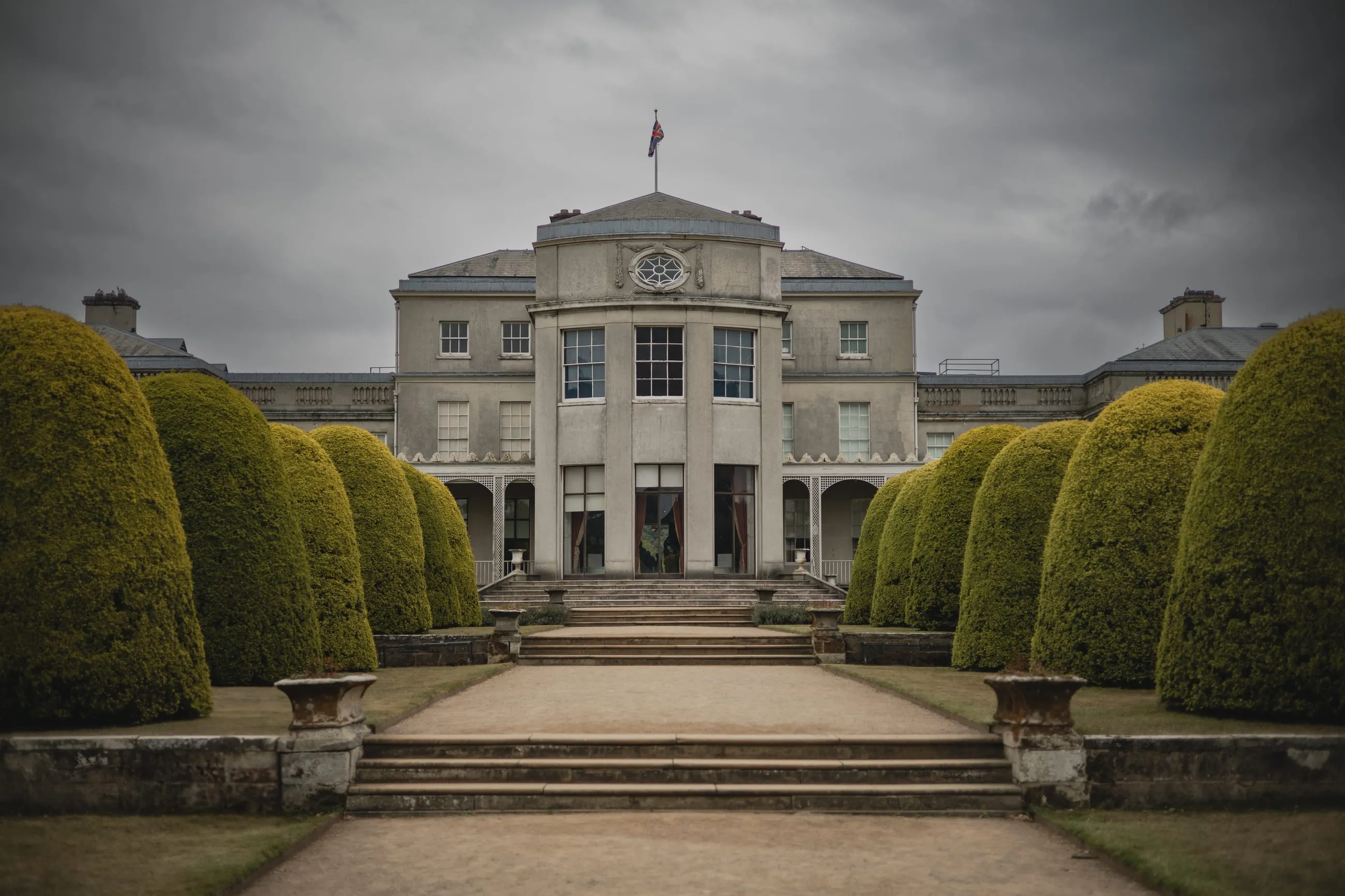 Neoclassical house front between clipped yew domes