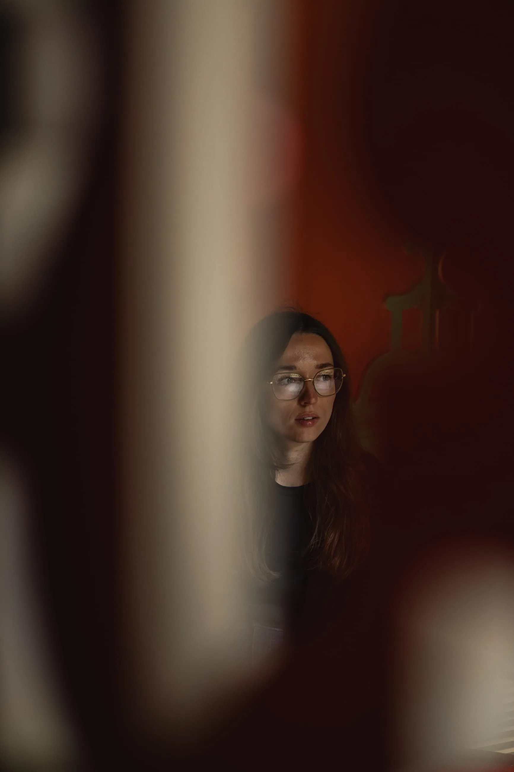 Woman's face glimpsed through a narrow red gap