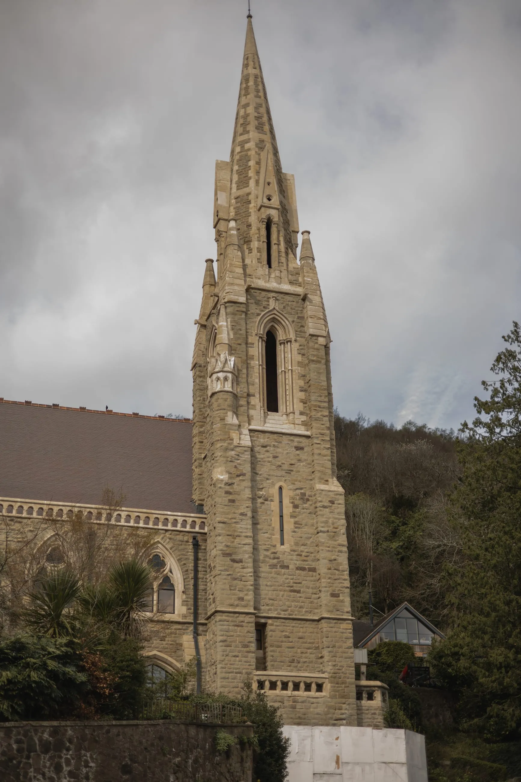 Stone church spire against wooded hillside