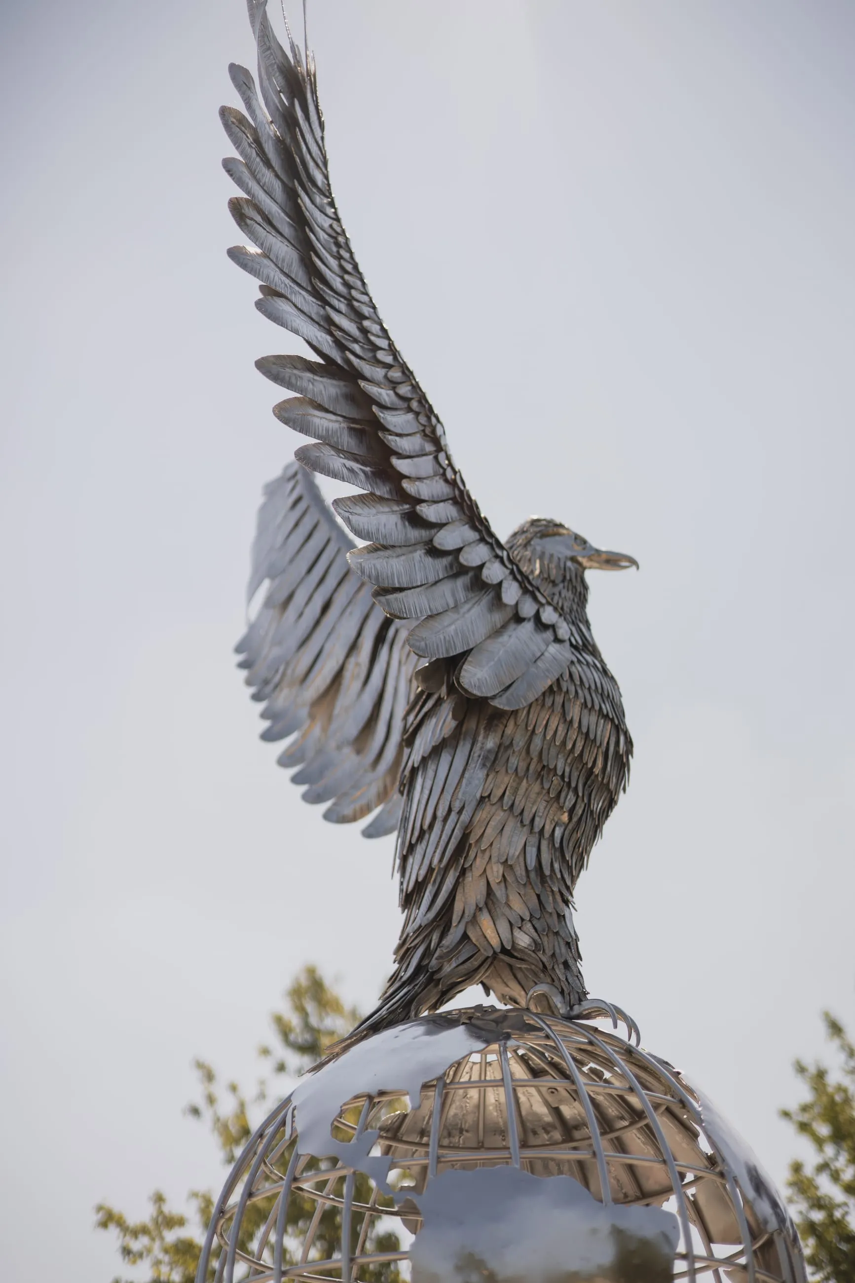 Steel eagle with raised wings against white sky