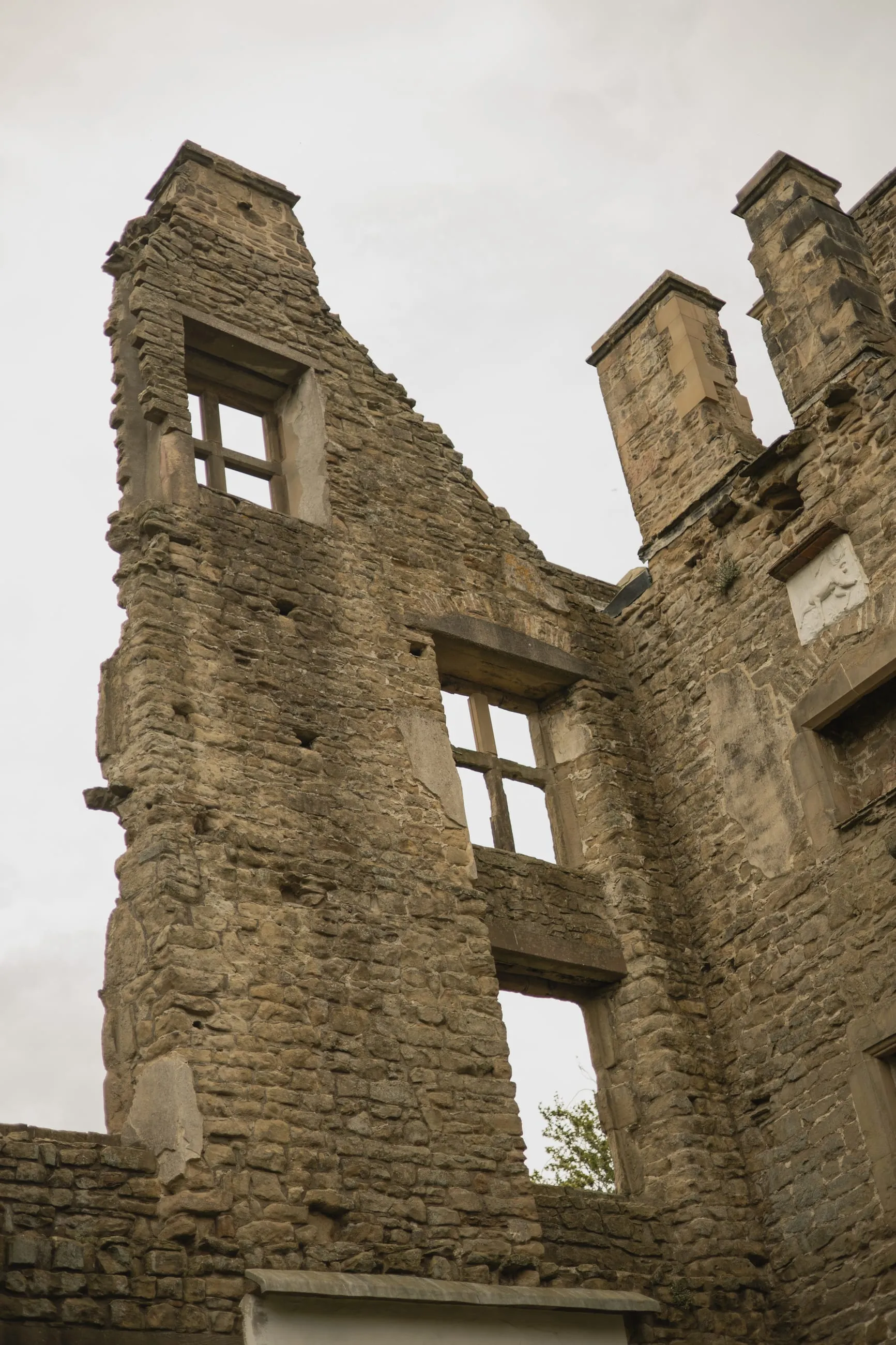 Roofless ruins of the Old Hall against grey sky