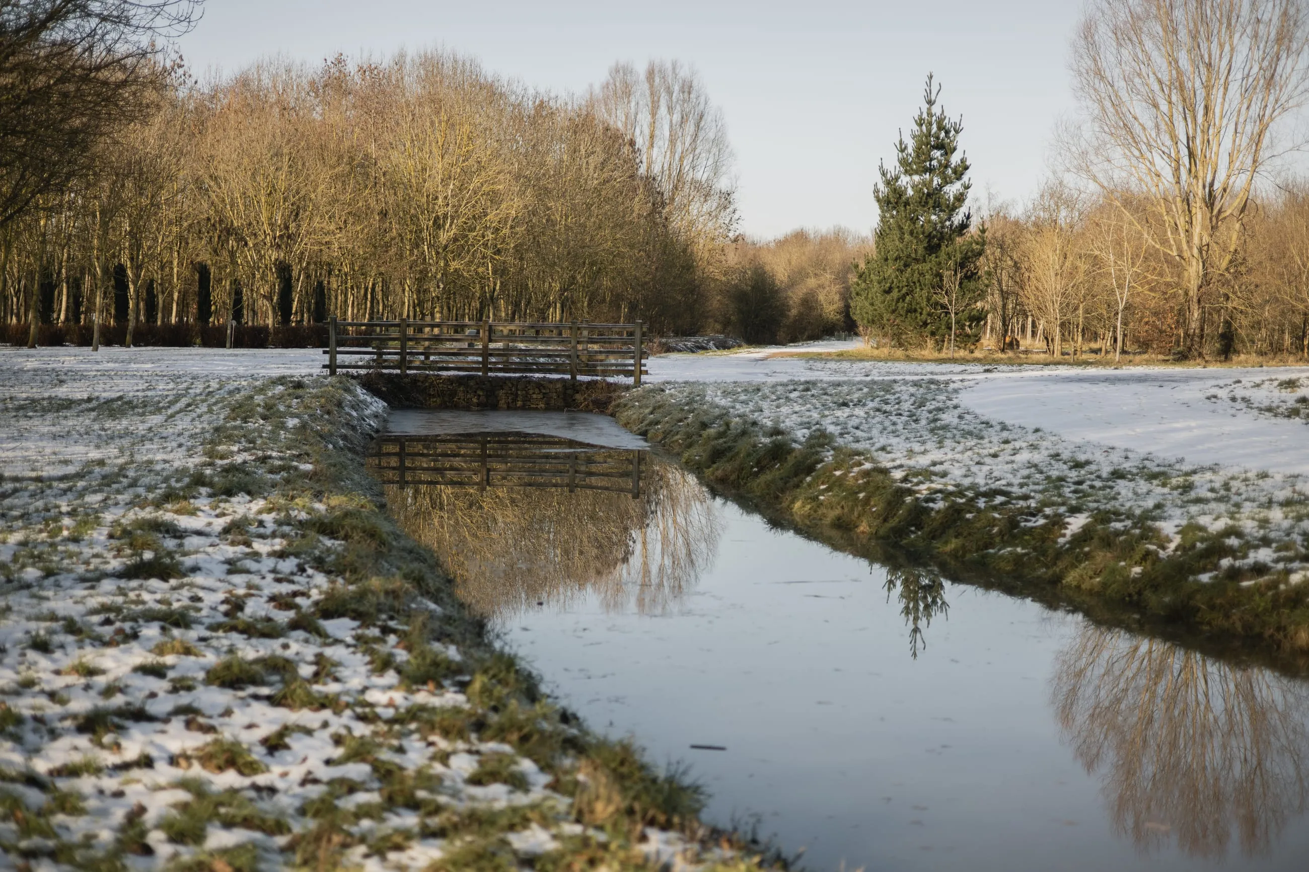 Stream reflecting sky between snowy banks