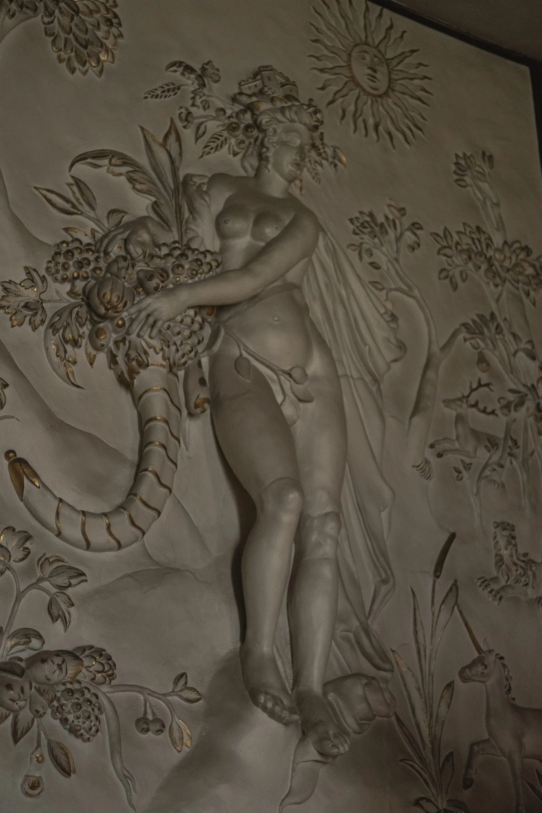 White plaster relief of a figure among foliage