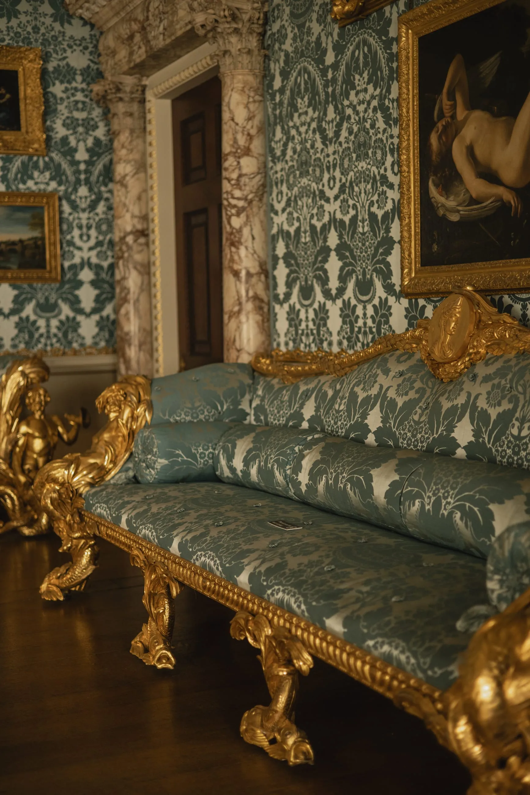 Gilded sofa with blue damask against matching walls