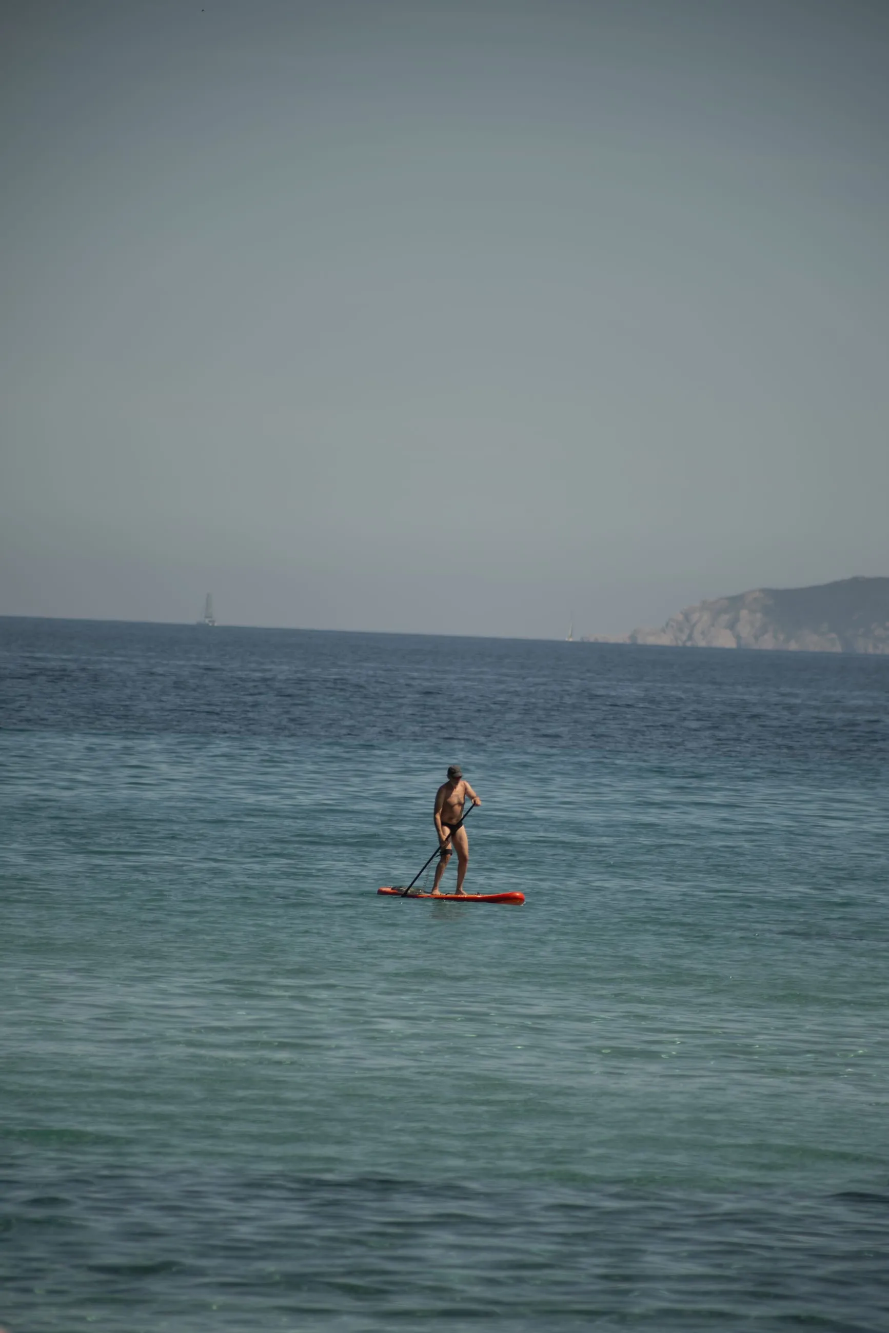 Lone paddleboarder on calm turquoise sea