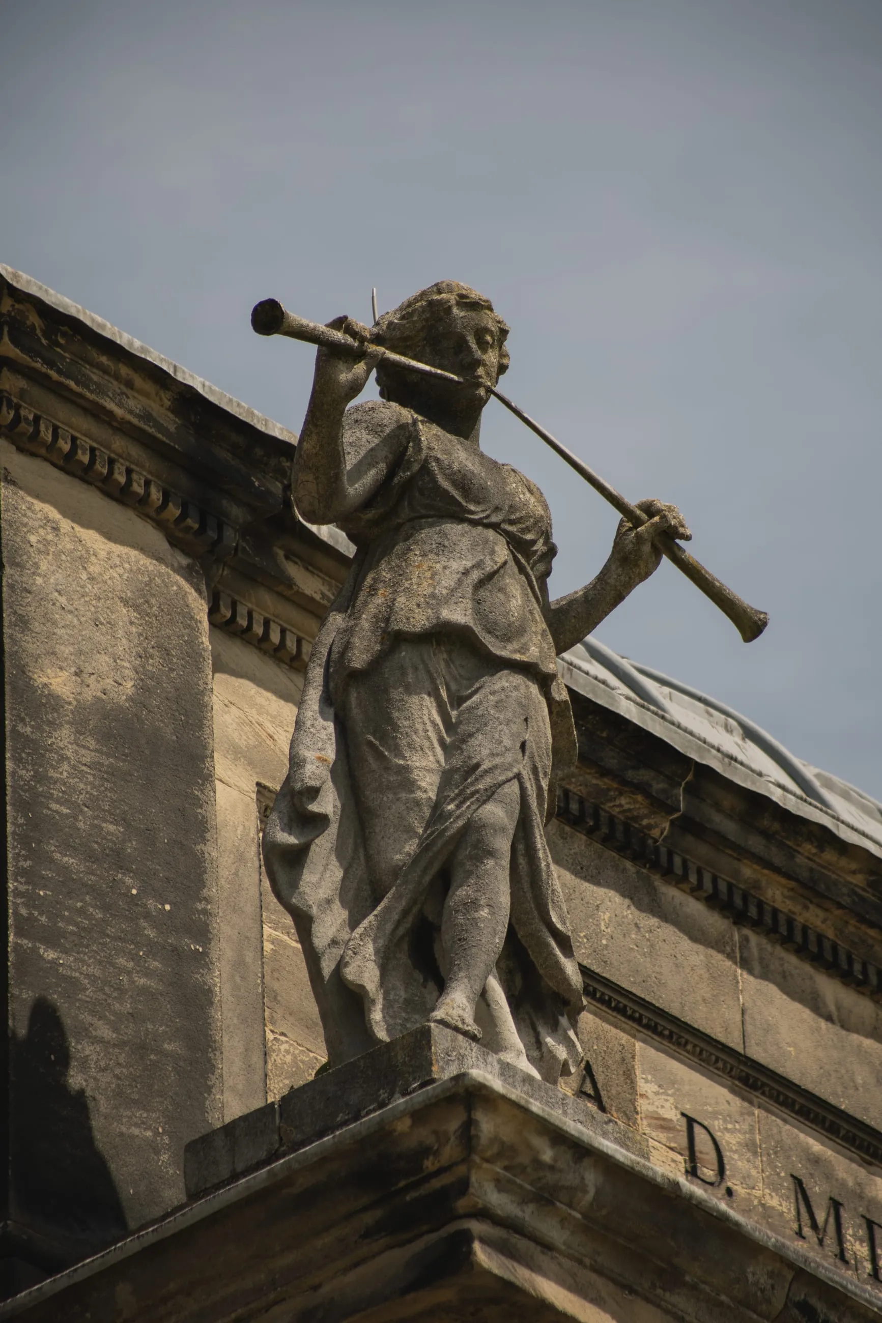 Rooftop statue with a horn against the sky
