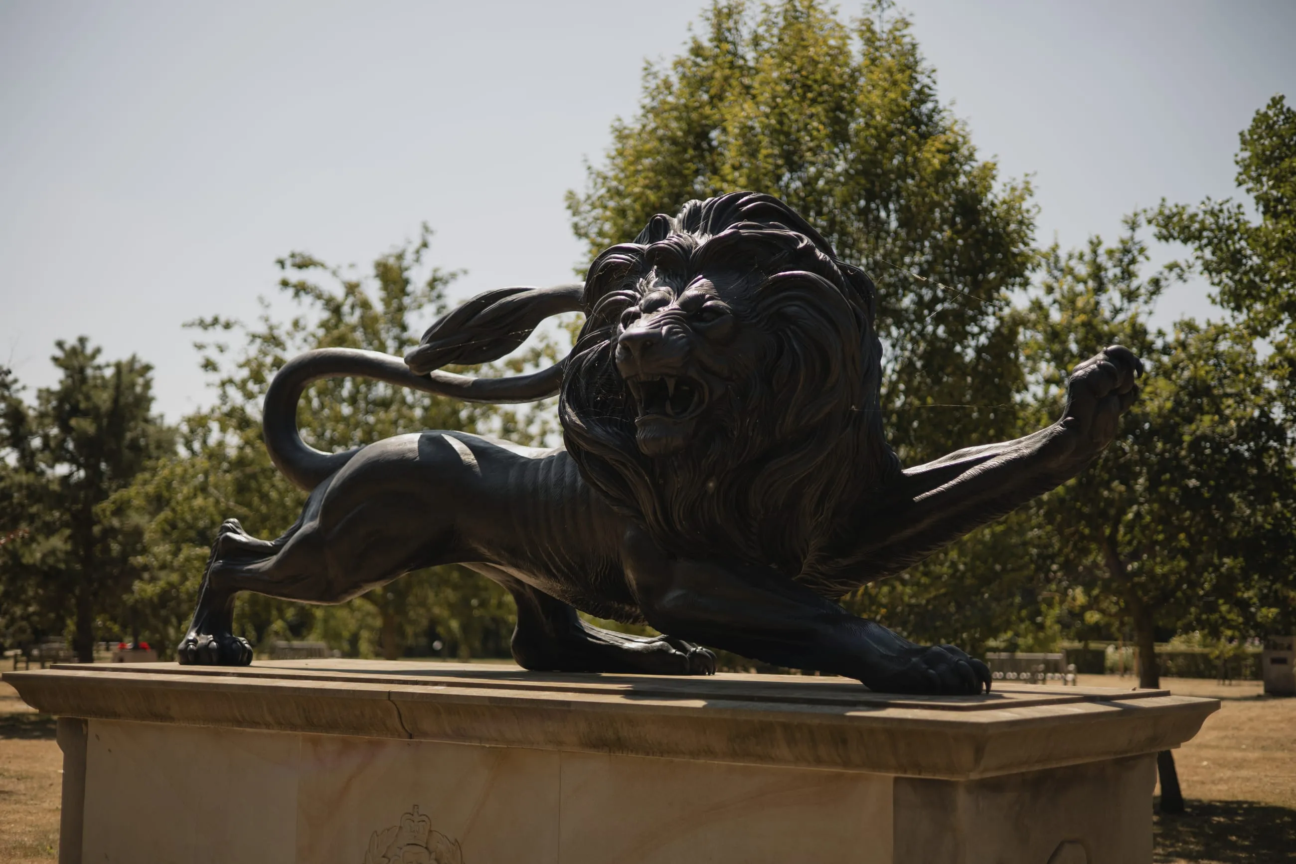 Bronze lion sculpture on a plinth in sunlight