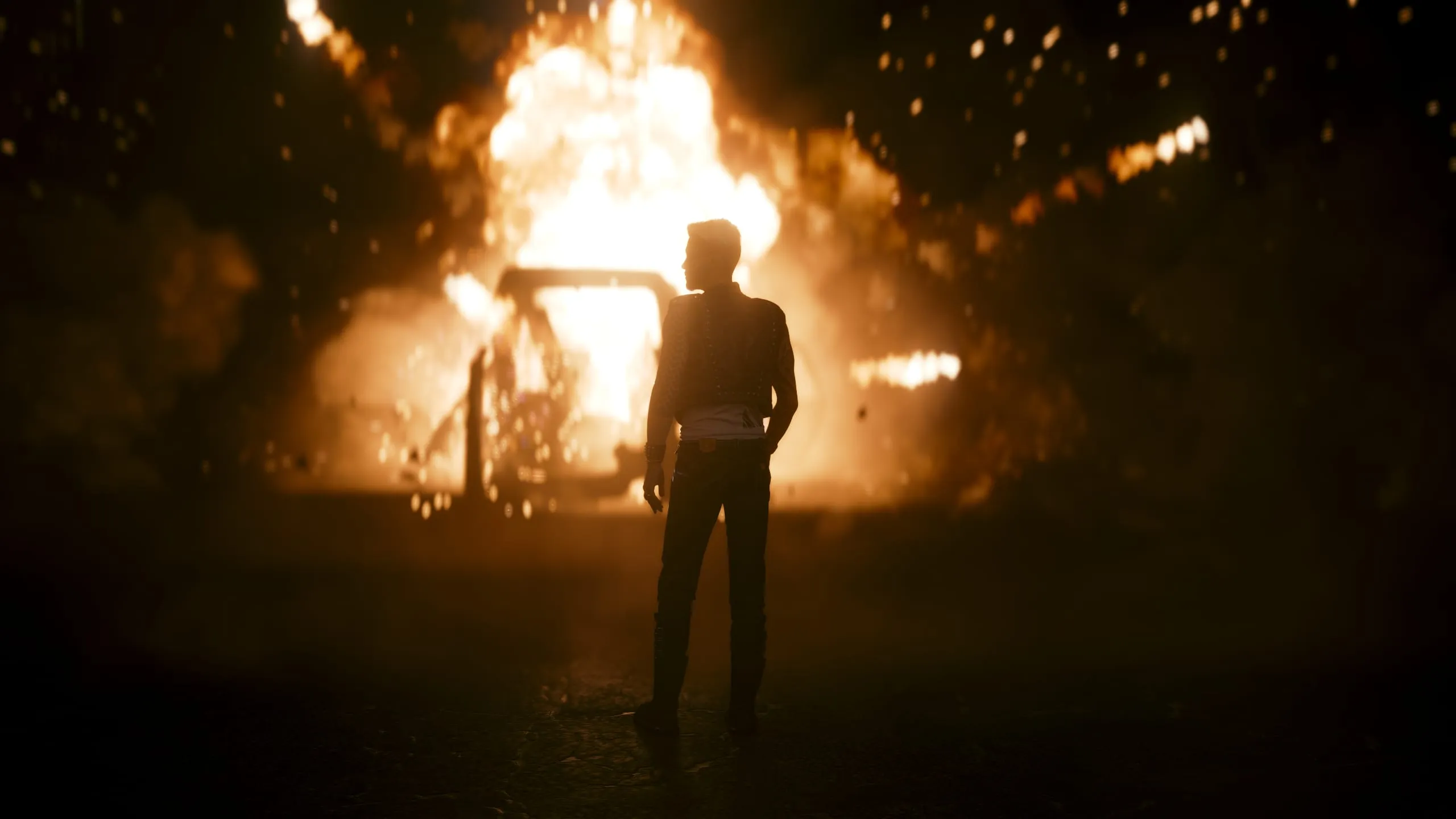 Man silhouetted, watching a car burn at night