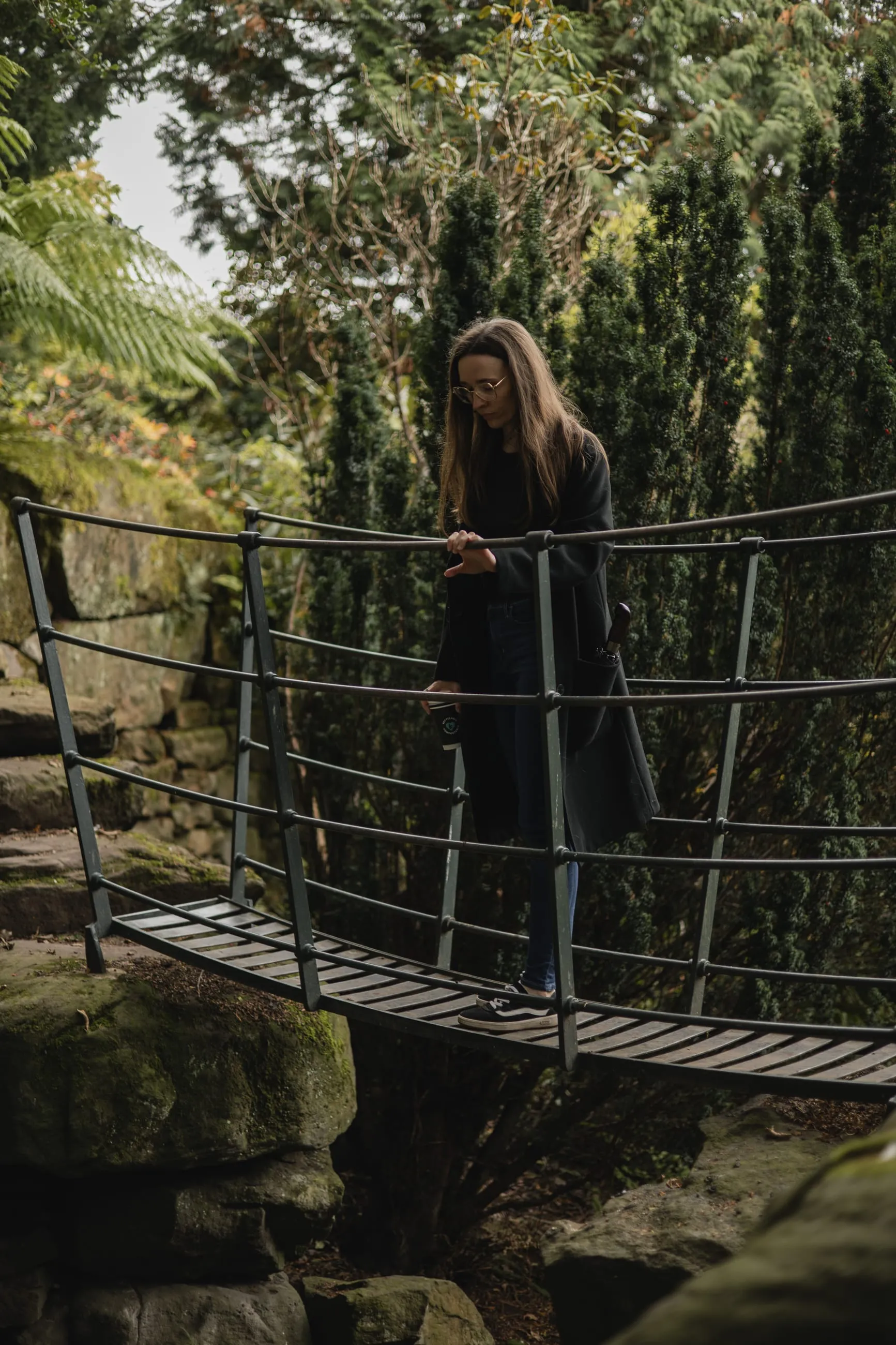 Woman on a rope bridge among conifers