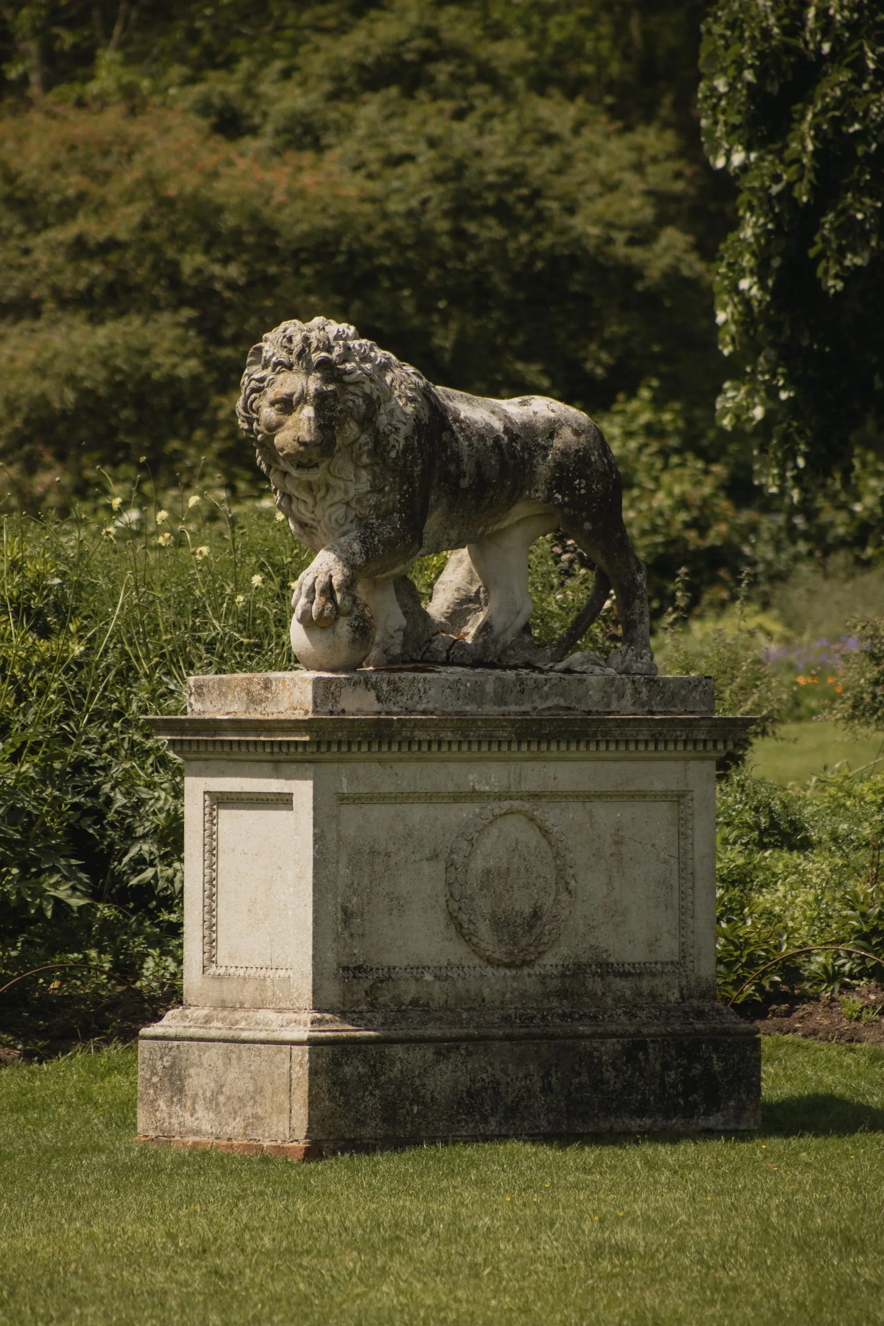 Stone lion on a plinth in parkland