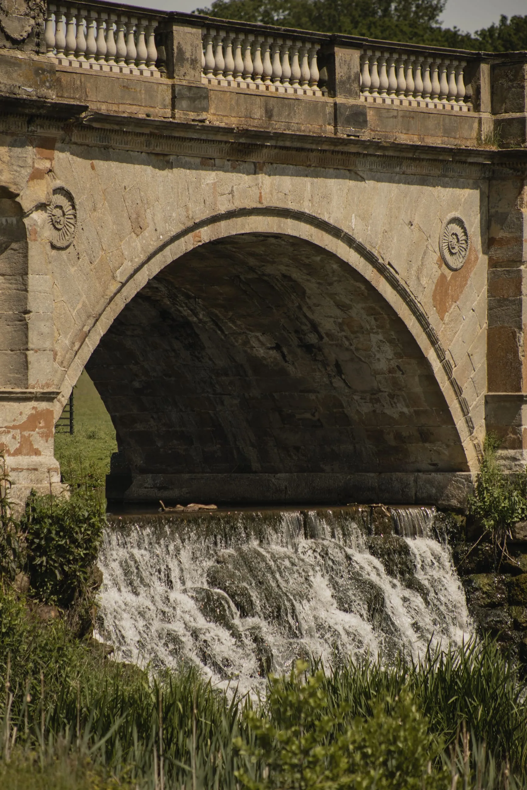 Water spilling under a stone bridge arch