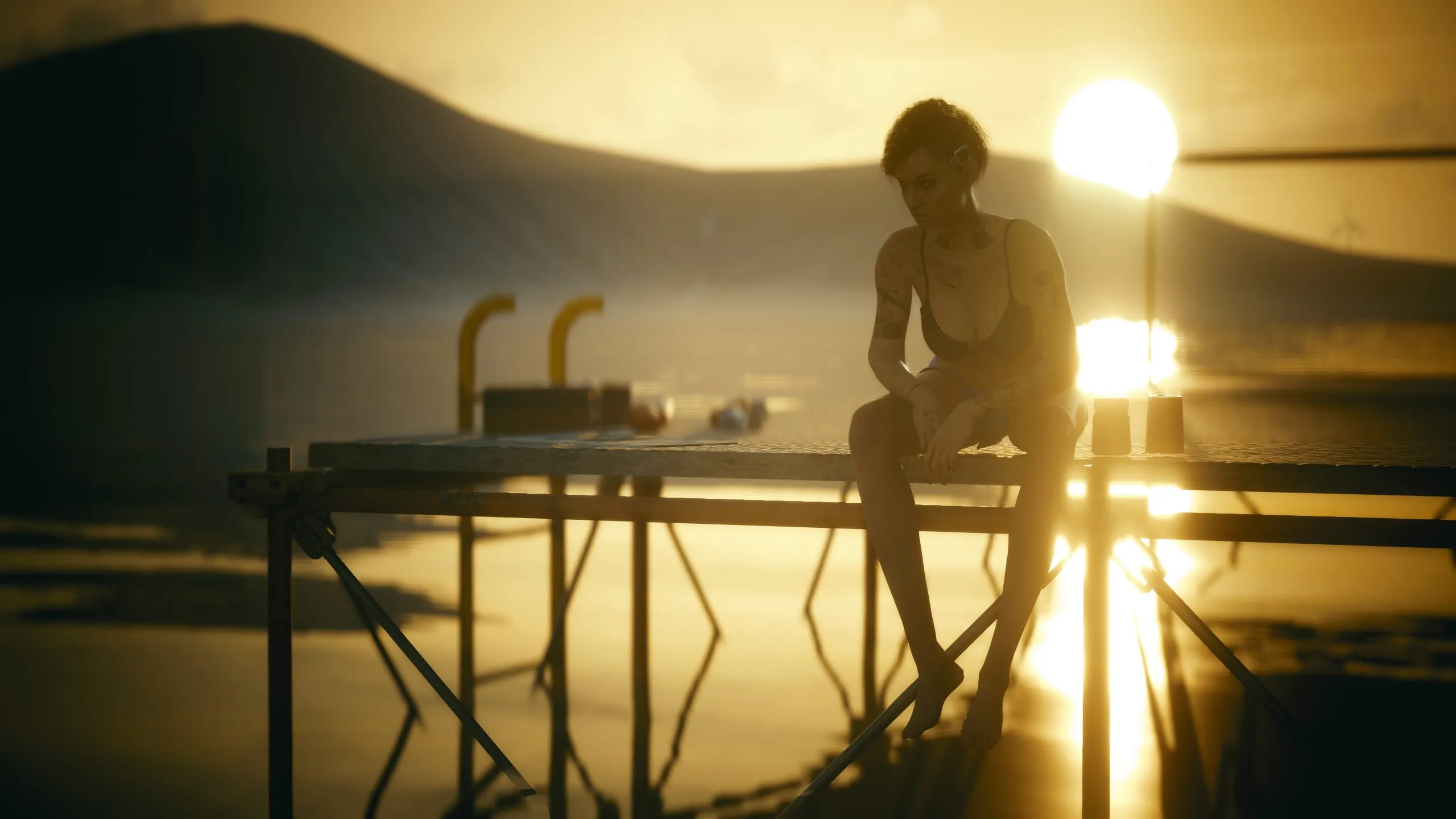 Woman sitting on a jetty, sun setting over water